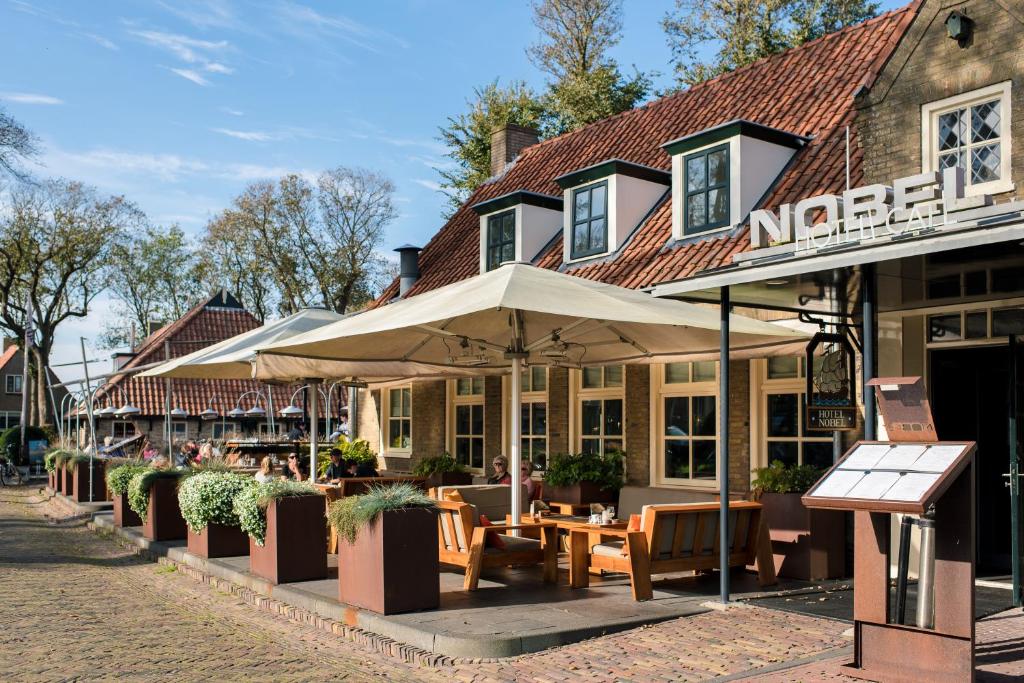 een restaurant met tafels en parasols in een straat bij Nobel Hotel Ameland in Ballum