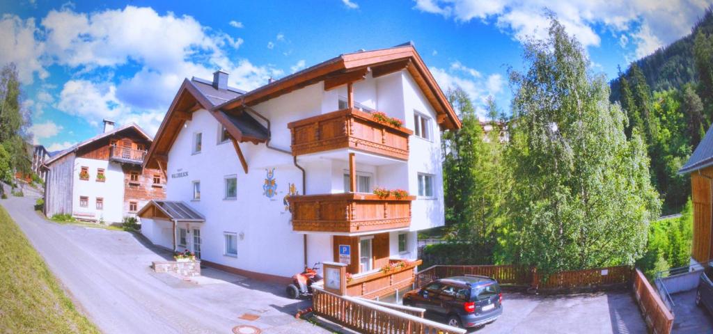 a large white house with wooden balconies on a street at Apart Waldblick in Serfaus