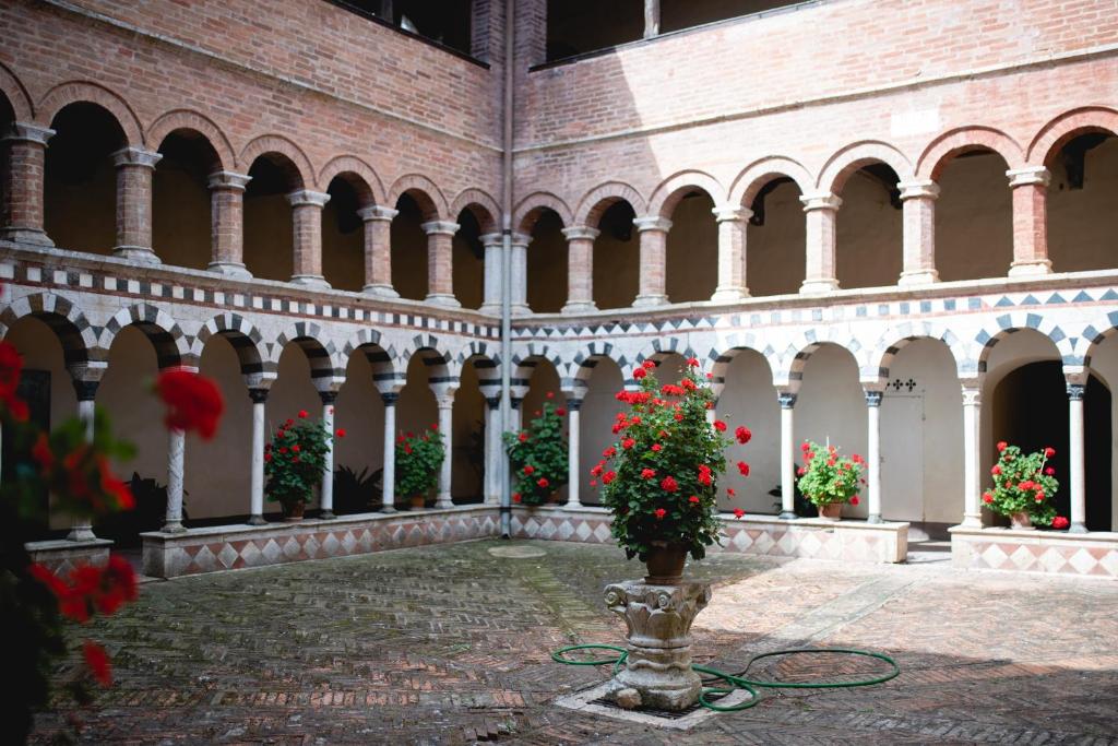 une cour avec des fleurs rouges dans un bâtiment dans l'établissement Antico Borgo di Torri, à Sovicille