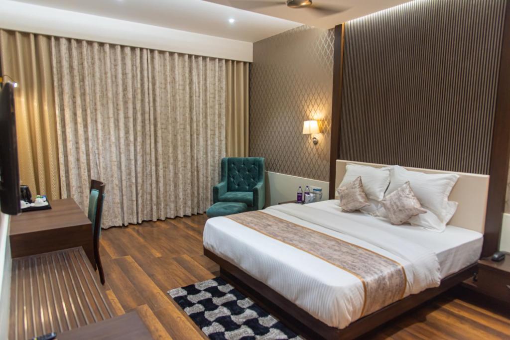a hotel room with a bed and a green chair at Royal Livin in Varanasi