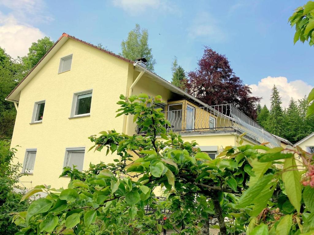 une maison jaune avec un balcon au-dessus dans l'établissement Ferienwohnung am Hörnle, à Königsfeld im Schwarzwald