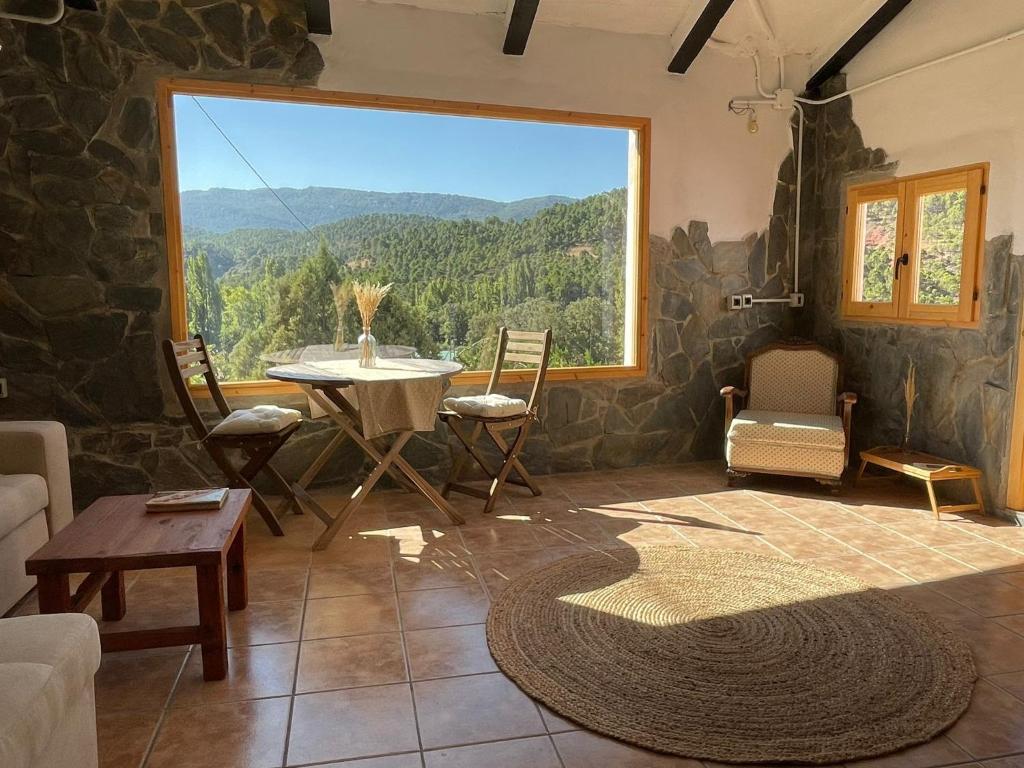 a living room with a table and a large window at Casa Rural El Carrizal in Riópar