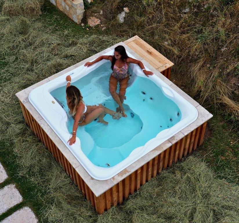 格雷札納的住宿－Ca' del Moro Wine Retreat，两个女孩在草地上的热水浴缸中