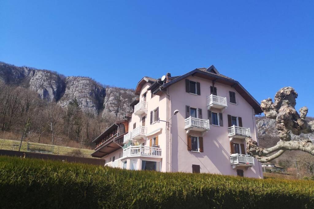 a white building on a hill with mountains in the background at Studio en bordure de Lac in Doussard