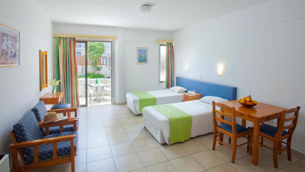 una camera d'albergo con due letti e un tavolo con sedie di Paloma Hotel Apartments a Ayia Napa