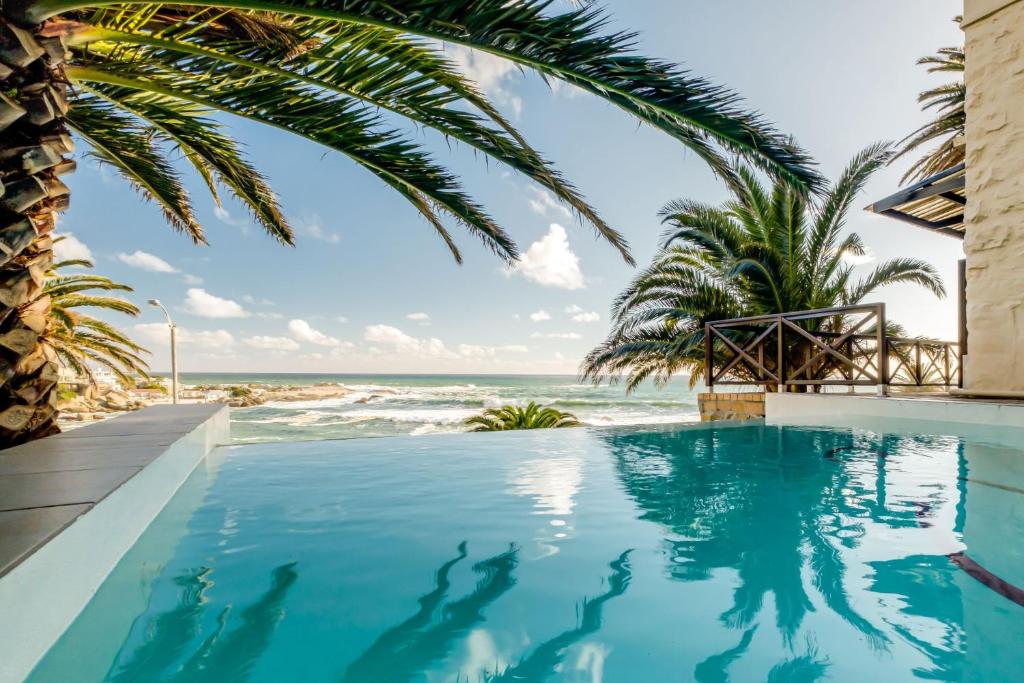 una piscina con la playa de fondo en Camps Bay Terrace Palm Suite, en Ciudad del Cabo