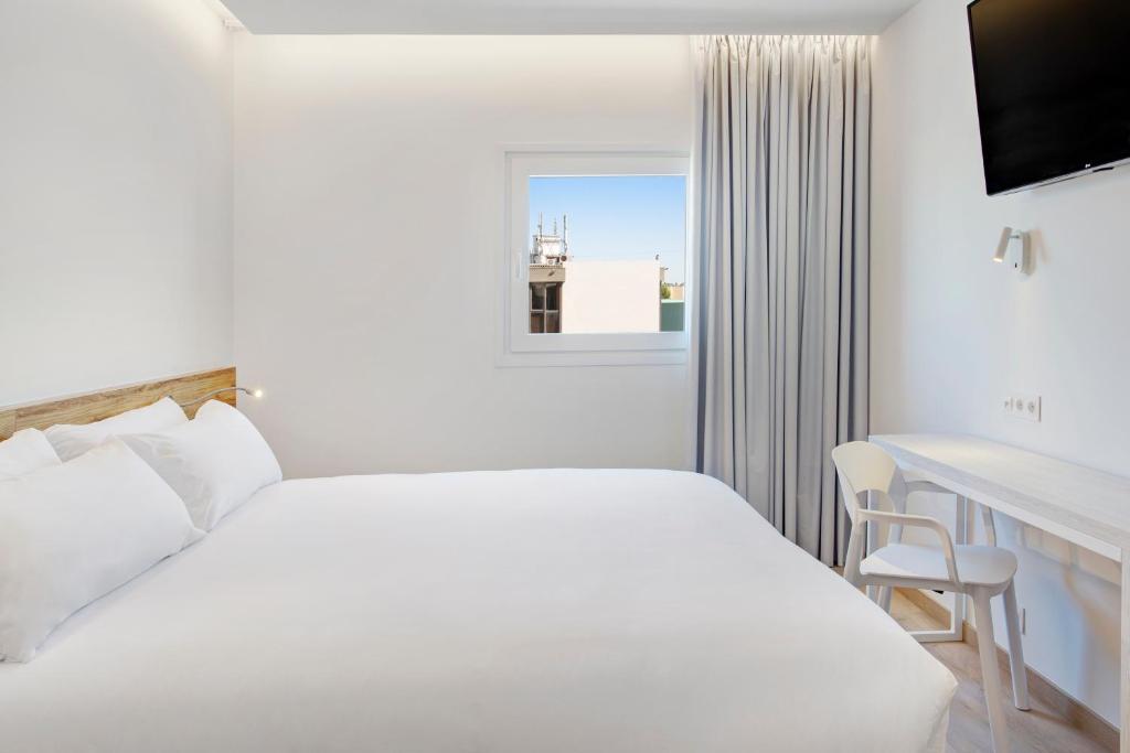 a white bedroom with a bed and a desk and a window at B&B HOTEL Porto Expo Aeroporto in Matosinhos