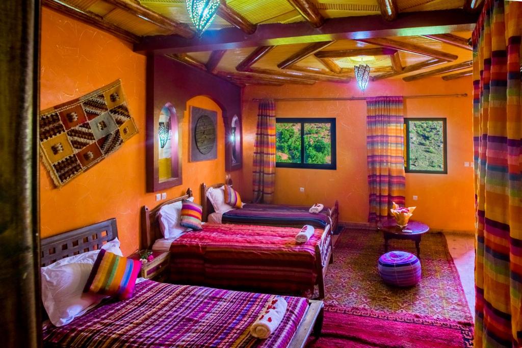 een slaapkamer met 2 bedden in een kamer met oranje muren bij Kasbah Imlil in Imlil