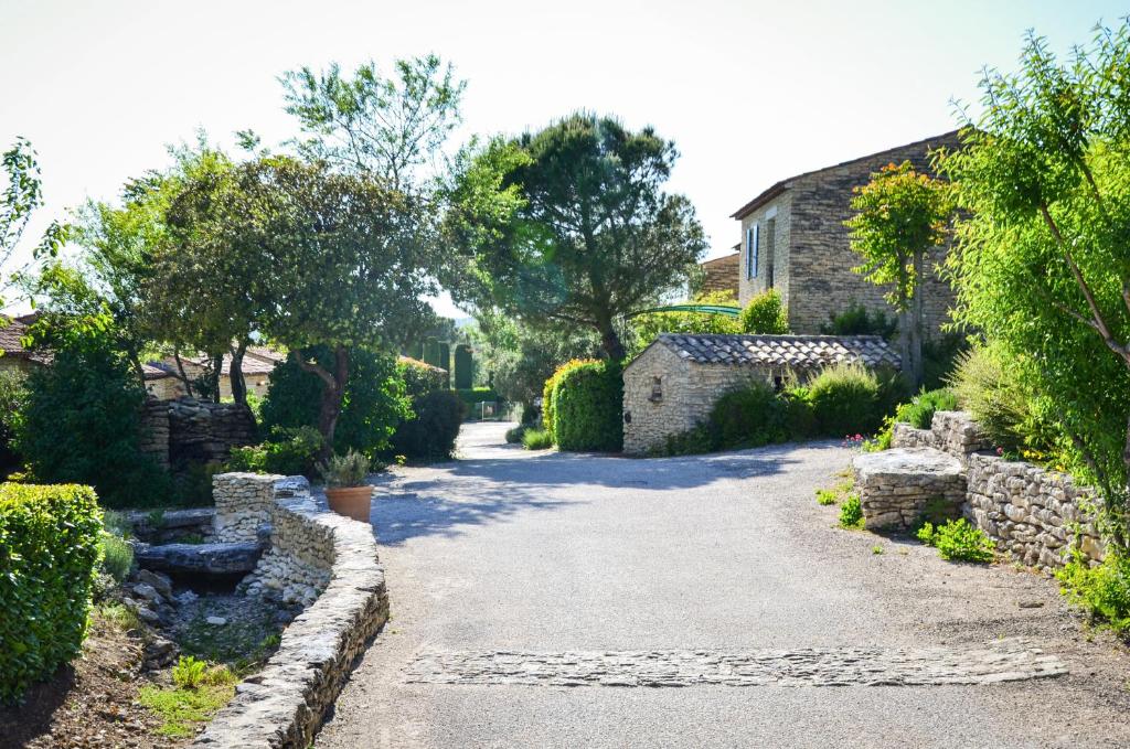 a driveway in a garden with stone buildings and trees at Cigale de Gordes in Gordes