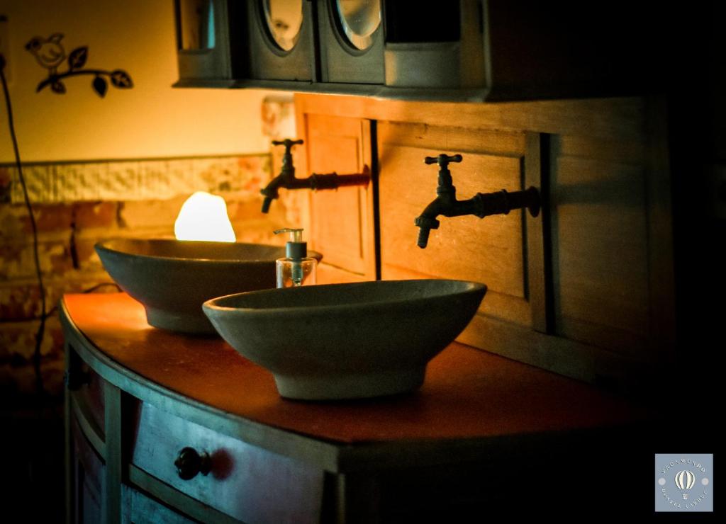 a bathroom with two sinks and two faucets at VagaMundo Hostel Carhue in Carhué