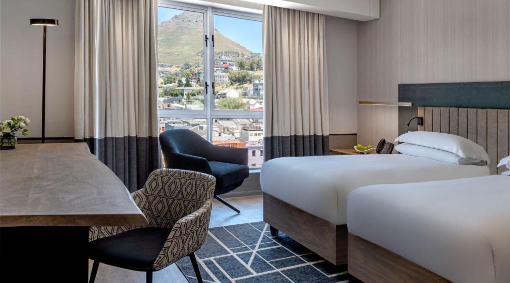 a hotel room with a bed, chair, desk and a window at Hyatt Regency Cape Town in Cape Town