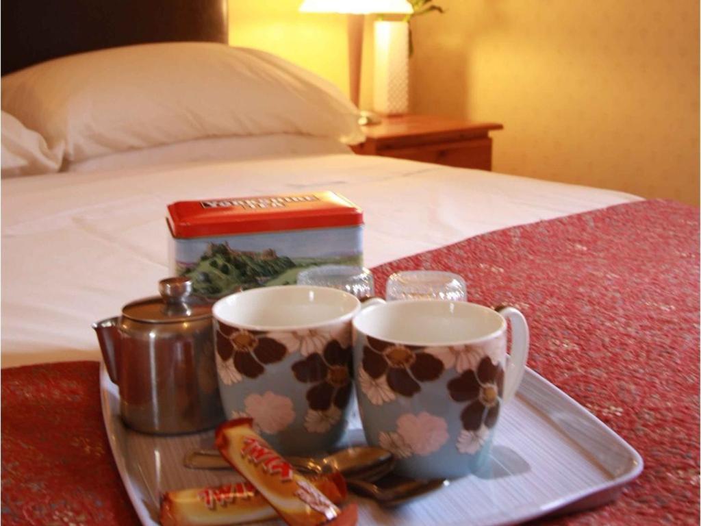 a tray with two coffee mugs on a bed at Murray House in Harrogate