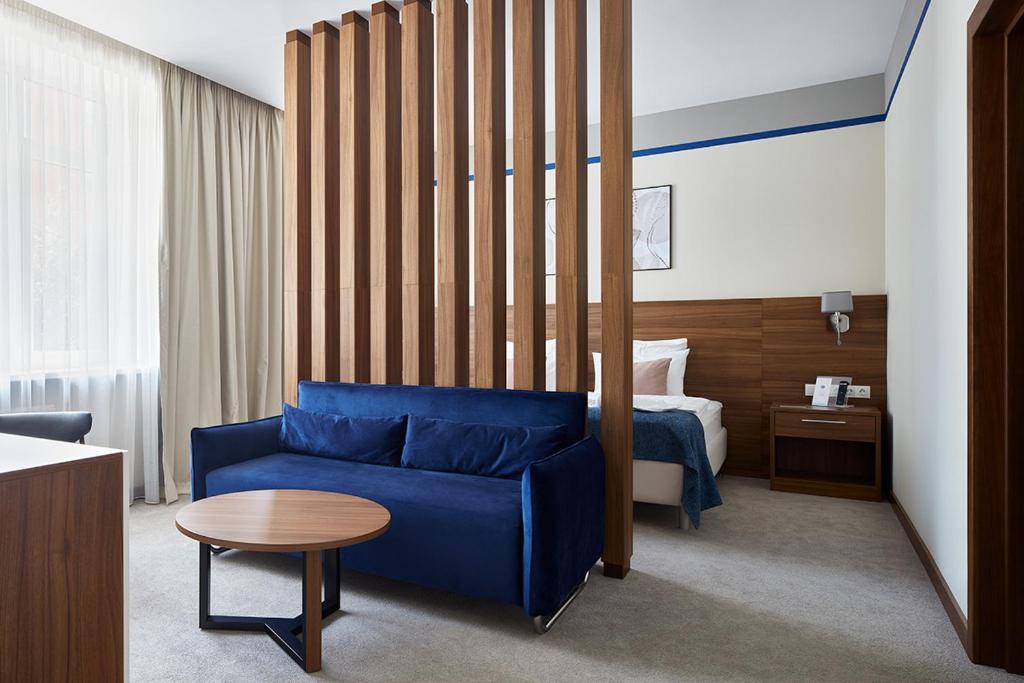 um quarto de hotel com um sofá azul e uma cama em Select Hotel Paveletskaya em Moscou