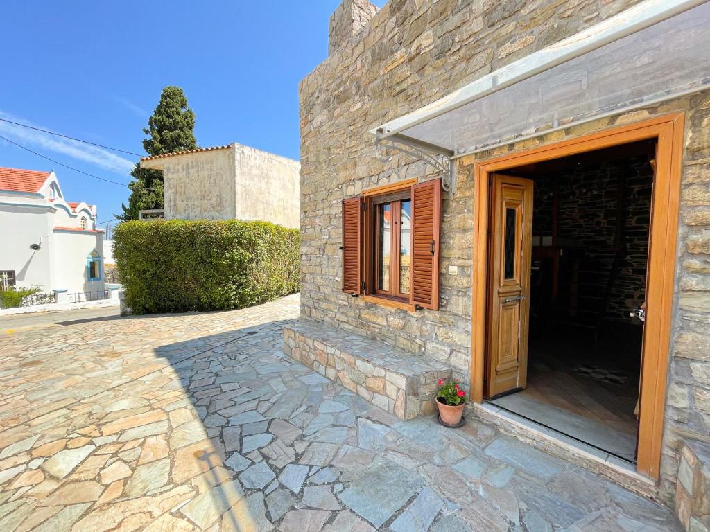 a stone house with a wooden door and a patio at Echo Traditional House - Ηχώ Παραδοσιακό Σπίτι in Émbonas