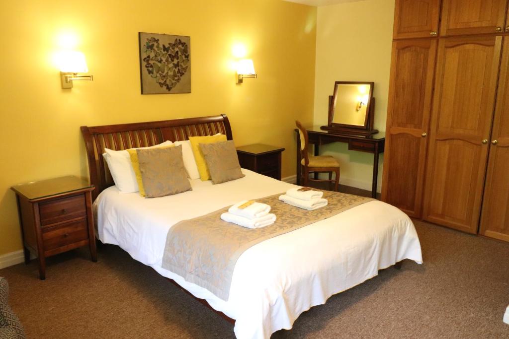 a bedroom with a bed with two towels on it at St George's Lodge, Bisley in Brookwood