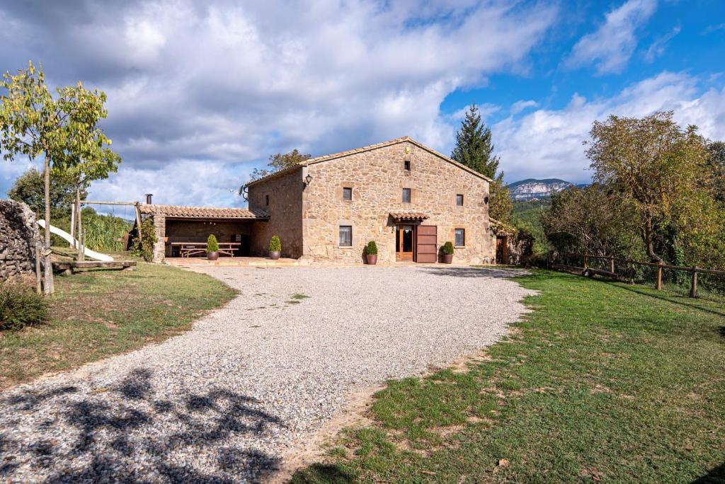 una vista exterior de una casa de piedra con entrada de grava en Casa Moixella, en Lladurs