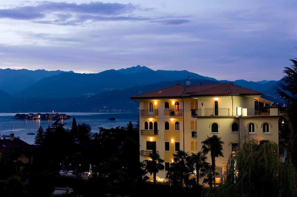 um edifício com vista para a água e as montanhas em Hotel Flora em Stresa