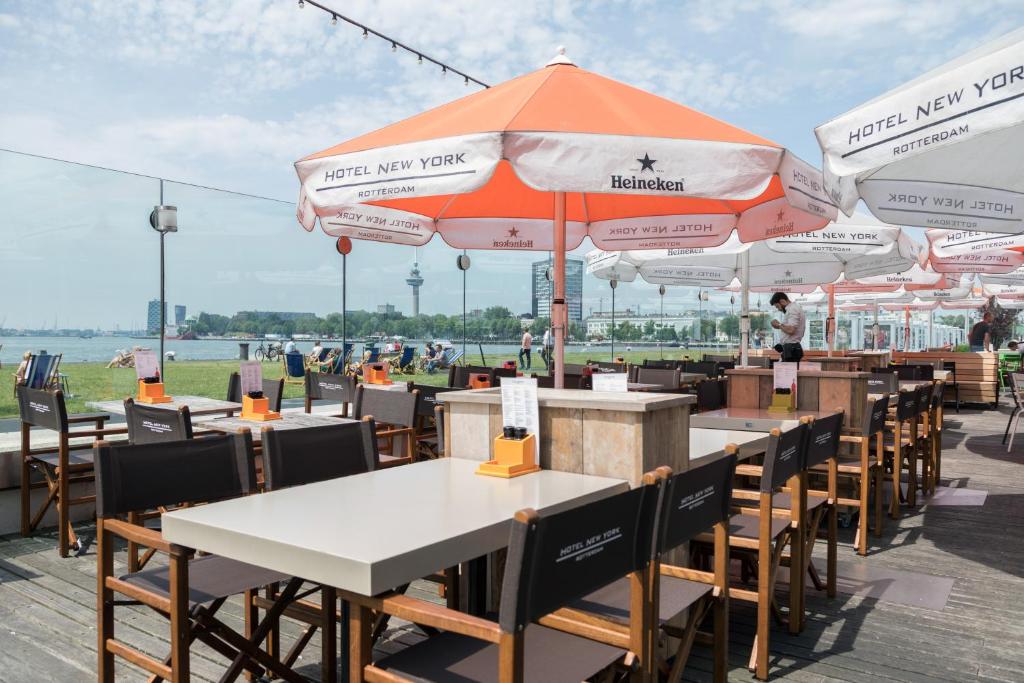 an outdoor restaurant with tables and chairs and umbrellas at Hotel New York by WestCord in Rotterdam
