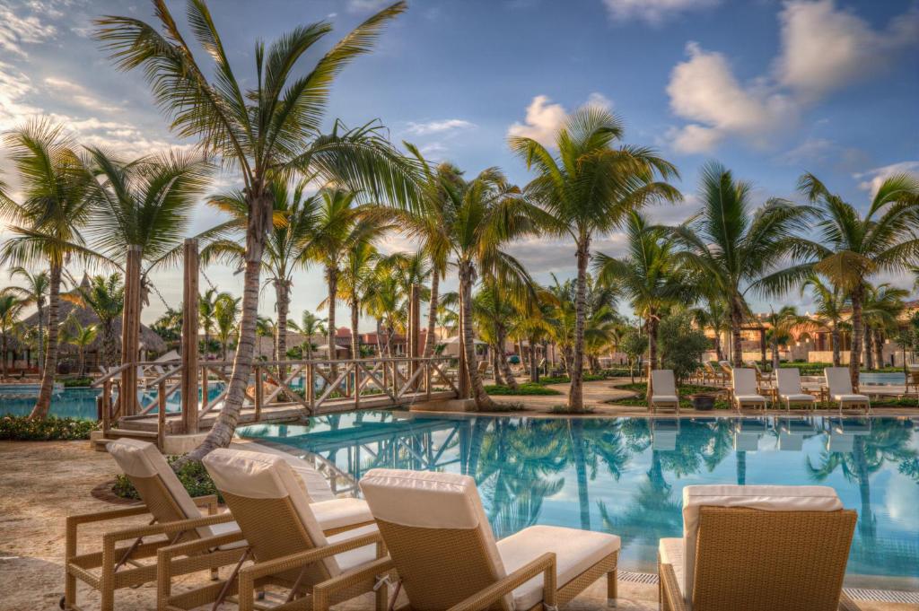 a resort pool with chairs and palm trees at Fishing Lodge Cap Cana in Punta Cana