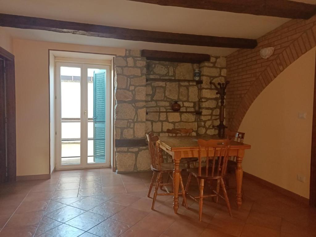 uma sala de jantar com uma mesa e uma parede de pedra em Deattellis House Casa vacanza em Campobasso
