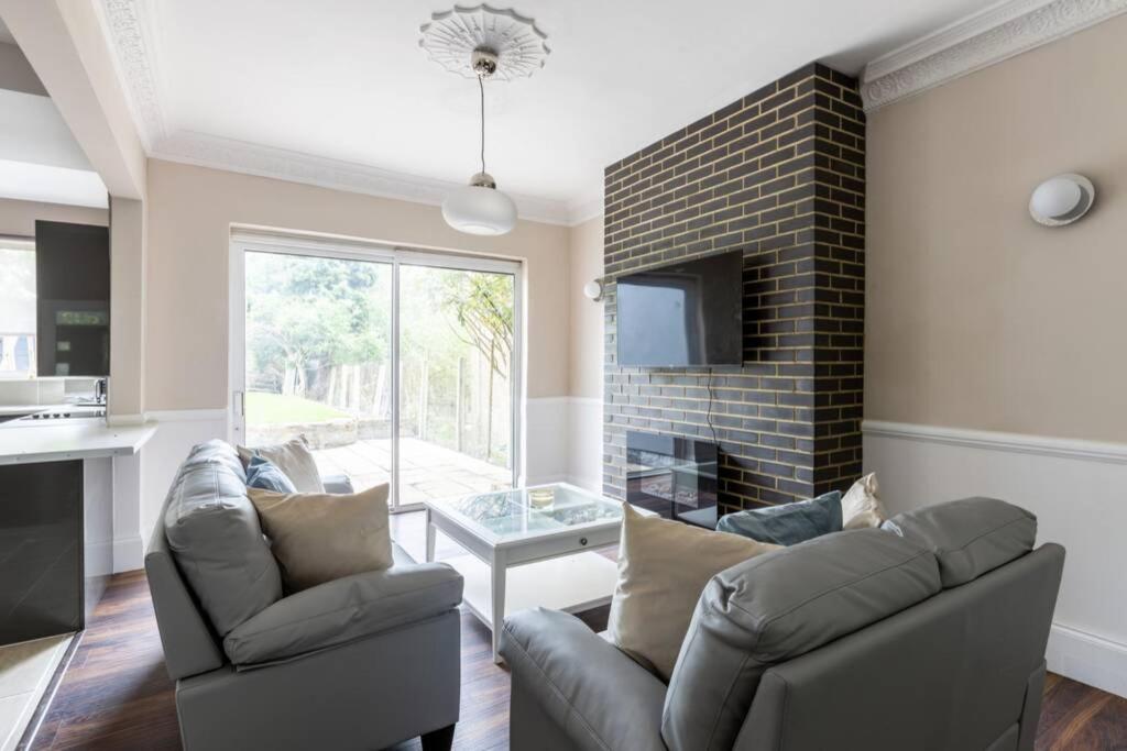 a living room with two chairs and a fireplace at The Cumbria House 5 bedroom House Stay in London