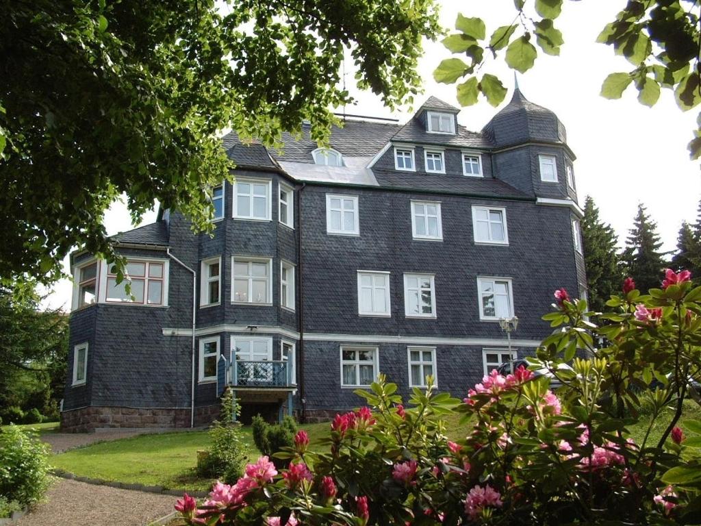 ein großes Backsteinhaus mit weißen Fenstern und Blumen in der Unterkunft Pension Haus am Waldesrand in Oberhof