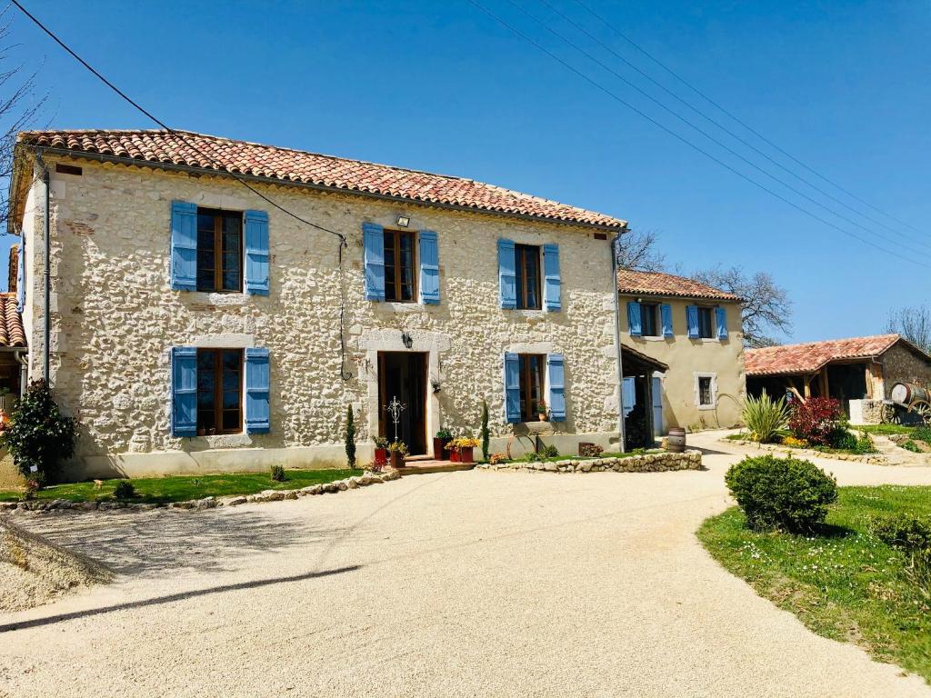 Casa de piedra con ventanas azules y entrada en Chez Brunet chambres d'hôtes et gîte, en Gondrin