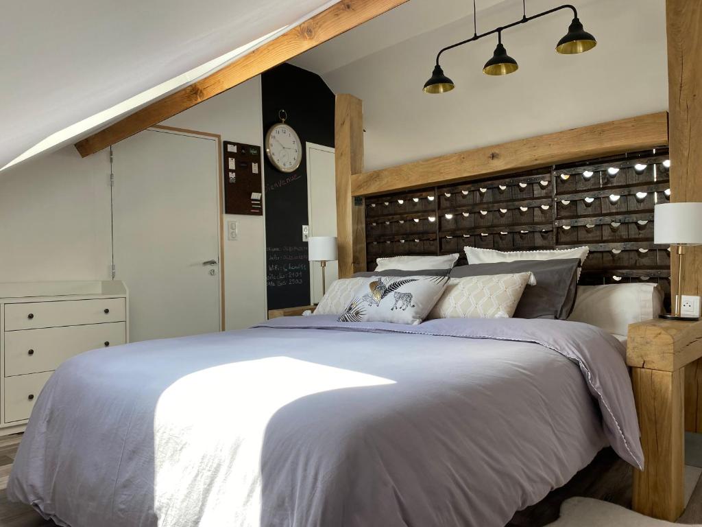 um quarto com uma cama grande e um relógio na parede em A la tête de Cheval em Épernay