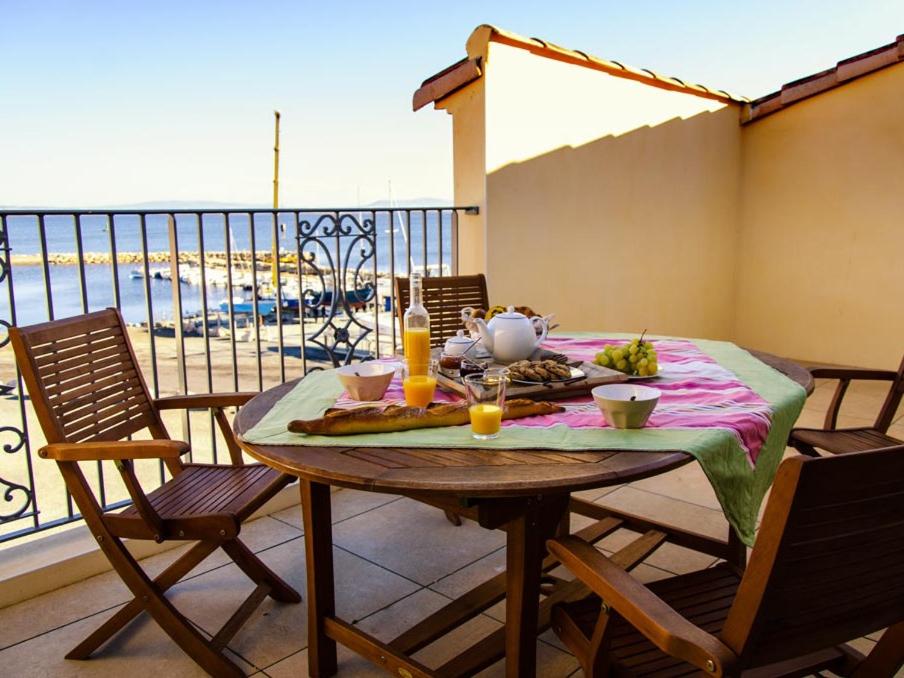 uma mesa com comida numa varanda com vista em Residence Farenc vue sur la lagune em Marseillan