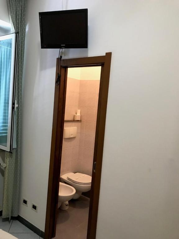 łazienka z toaletą i telewizorem na ścianie w obiekcie Hotel Amico Fritz w mieście Livorno