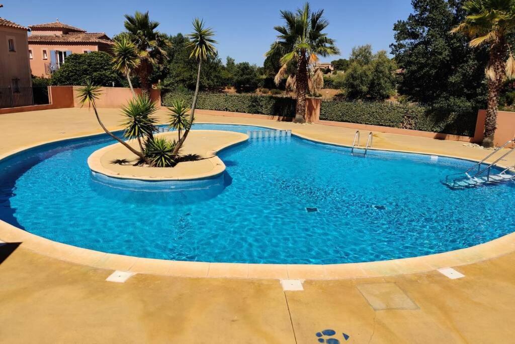 a large blue swimming pool with palm trees in it at Appartement Golf Saint Thomas - Belle résidence in Béziers