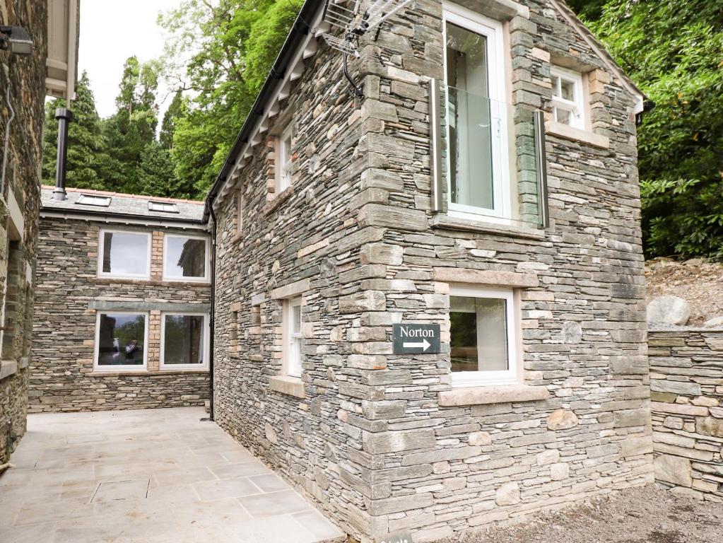 a stone house with a stone wall and a driveway at Norton in Keswick