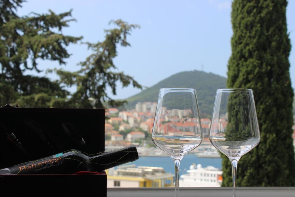 two wine glasses sitting on a table with a view of a city at Aquamarine Deluxe Apartment in Dubrovnik