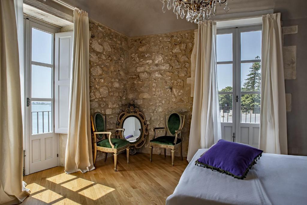 a bedroom with a bed and chairs and a mirror at Dimora Aretusa Luxury in Siracusa