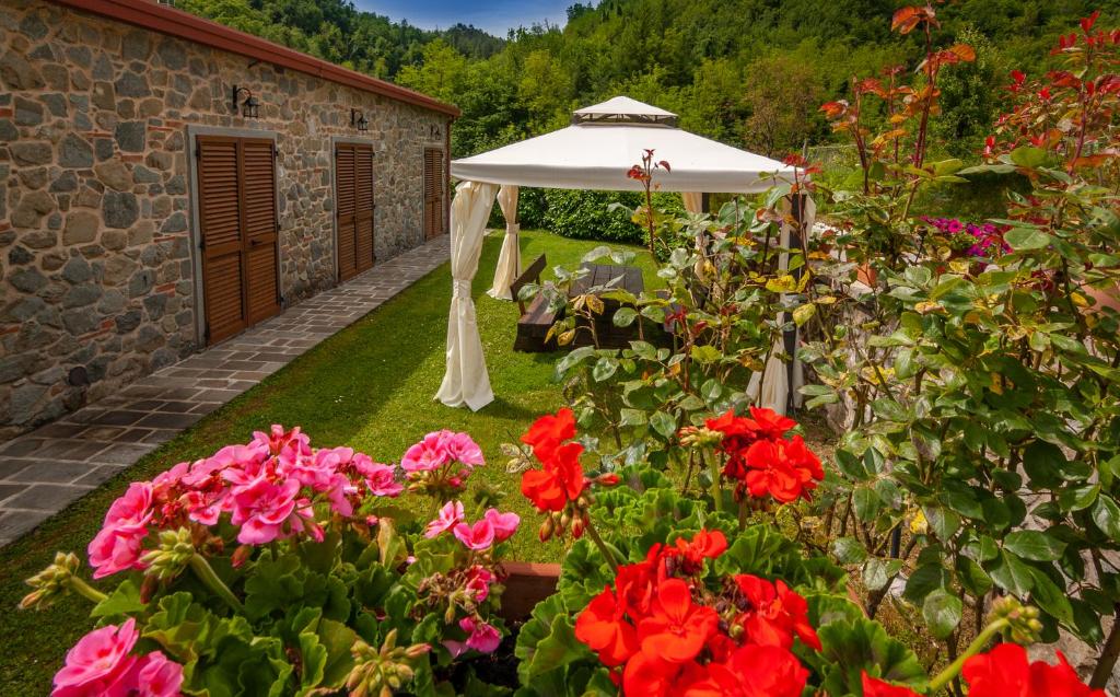 a garden with a white umbrella and red flowers at casa vacanze in Garfagnana in Gallicano