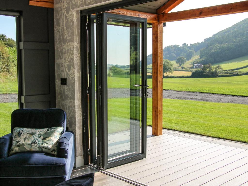 a chair on a porch with a sliding glass door at Meadow View in Meifod