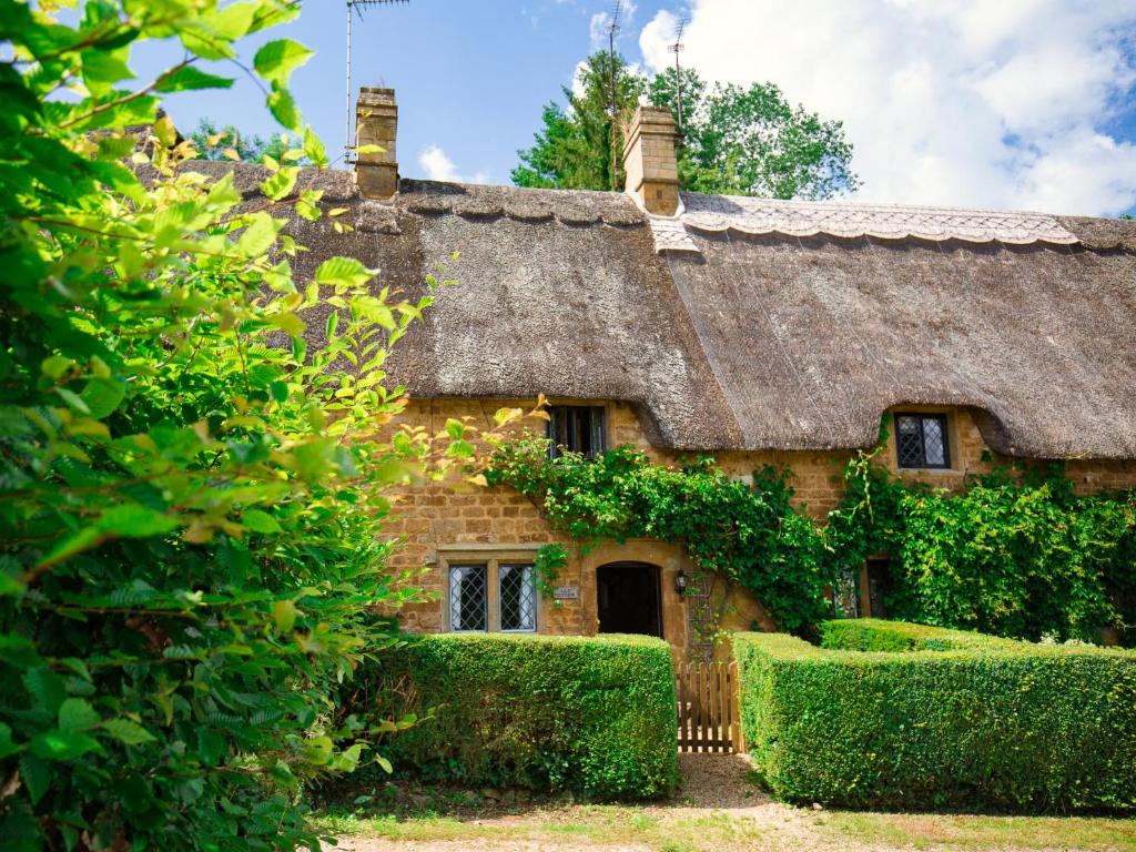 an old stone cottage with a thatched roof at Lily Cottage in Great Tew