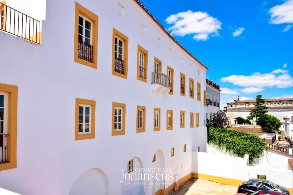a white building with yellow windows on a street at Noble House Essence Évora - by Unlock Hotels in Évora