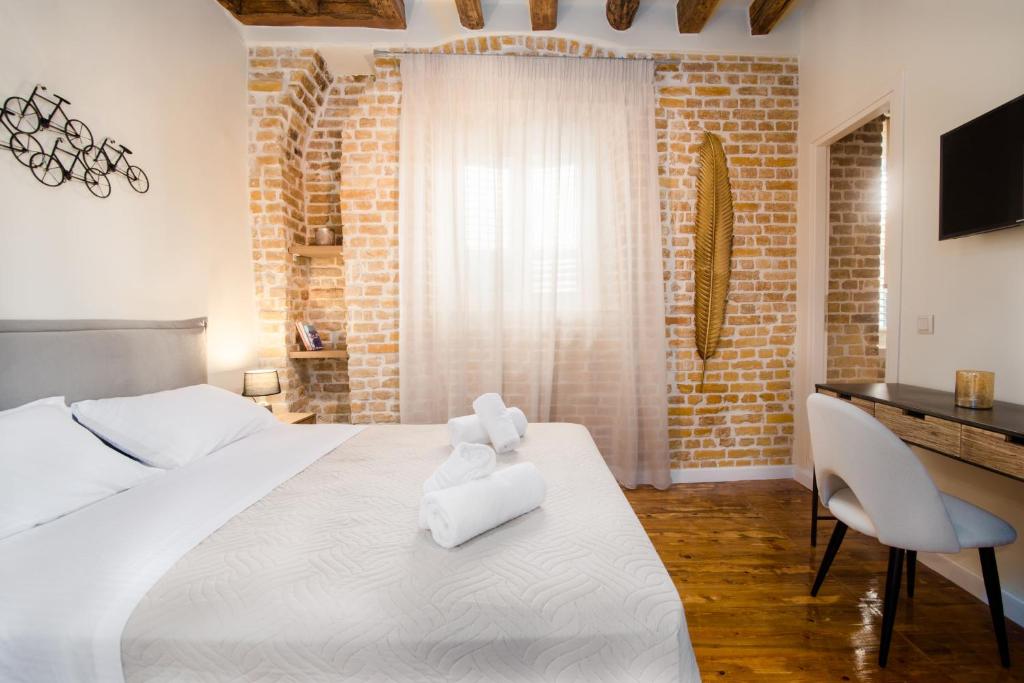 1 dormitorio con 1 cama blanca grande y escritorio en Curcumelli Luxury Suites - ΚΟΡΚΥΡΑ en Corfú