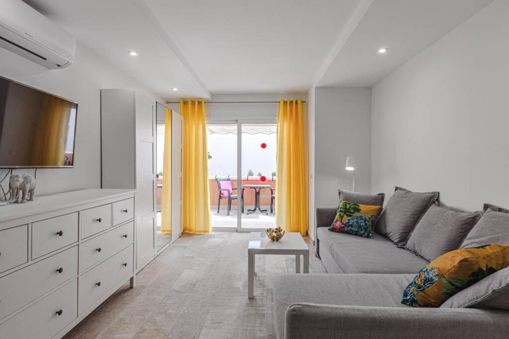 a living room with a gray couch and yellow curtains at Tenerife Royal Gardens One Bedroom Apartment in Playa de las Americas