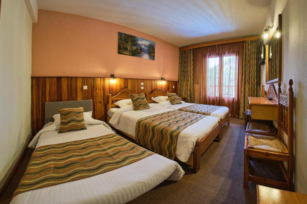 a hotel room with two beds and a table at Hotel Victoria in Metsovo
