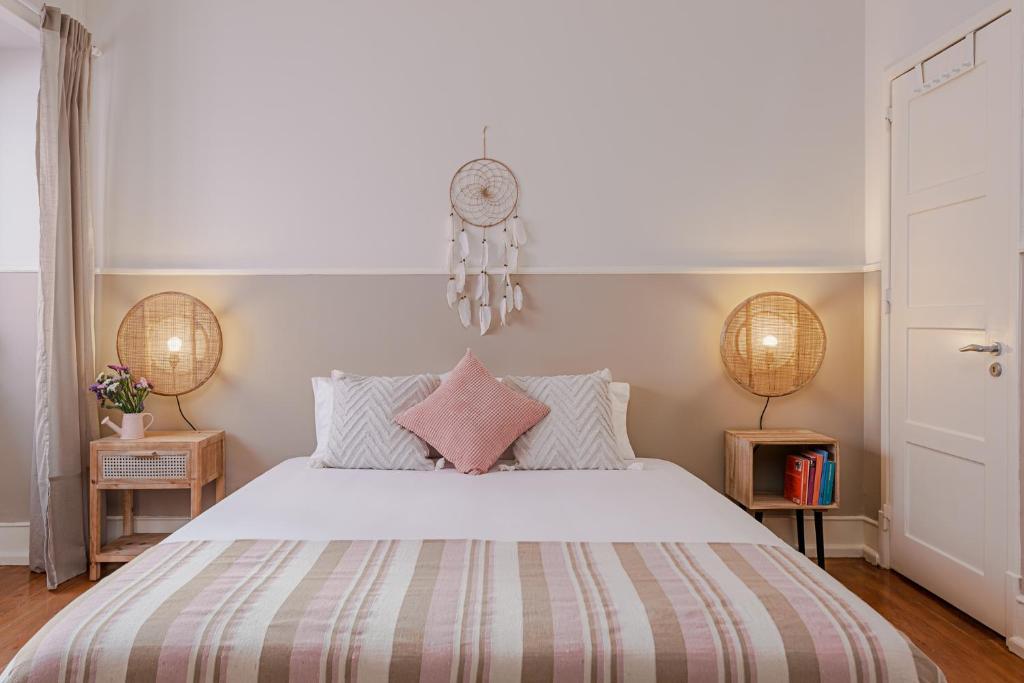 um quarto com uma grande cama branca com almofadas cor-de-rosa em The Local Guest House Lisbon em Lisboa