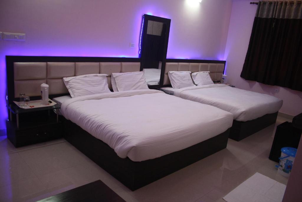 - 2 lits dans une chambre d'hôtel avec des lumières violettes dans l'établissement Hotel Golden sky, à Lucknow
