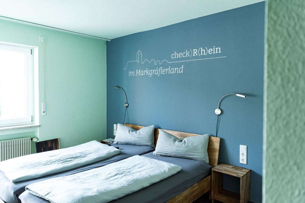 1 dormitorio con 2 camas y pared azul en Hotel Check-Rhein - Self Check-in en Neuenburg am Rhein