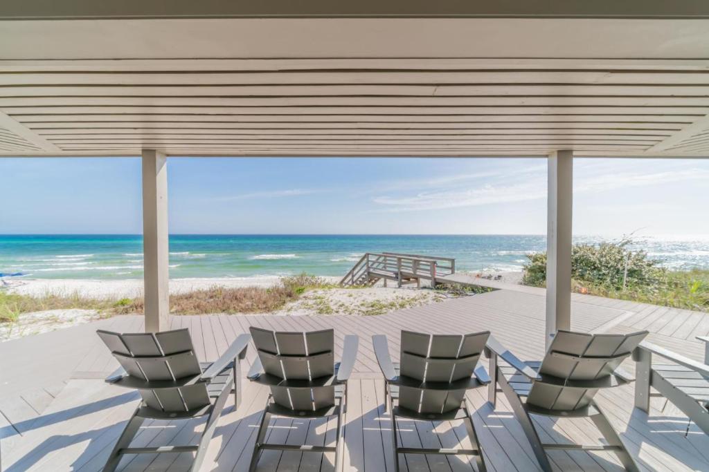 a group of chairs sitting on a patio overlooking the ocean at Nifty Shades Of Gray Home in Inlet Beach