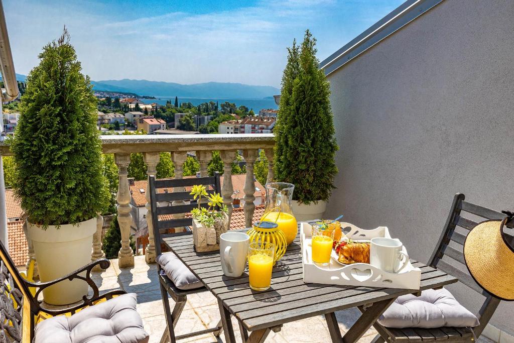 einen Holztisch mit Frühstückszutaten auf dem Balkon in der Unterkunft Apartmani Kaiserin in Crikvenica
