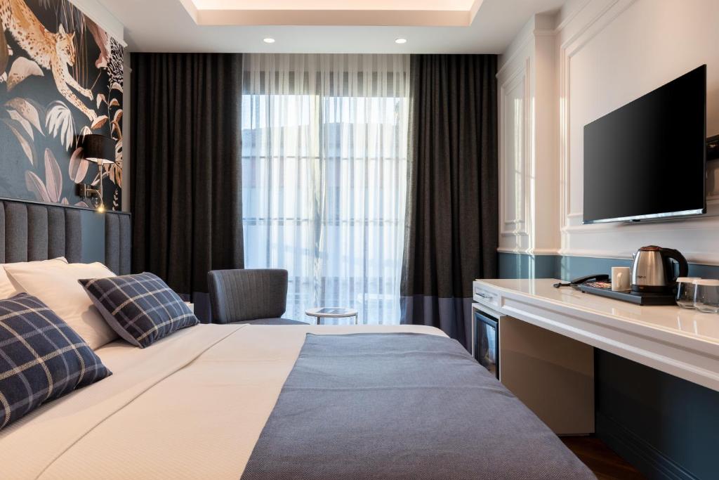 a hotel room with a bed and a flat screen tv at Motif Hotel Çeşme in Çeşme