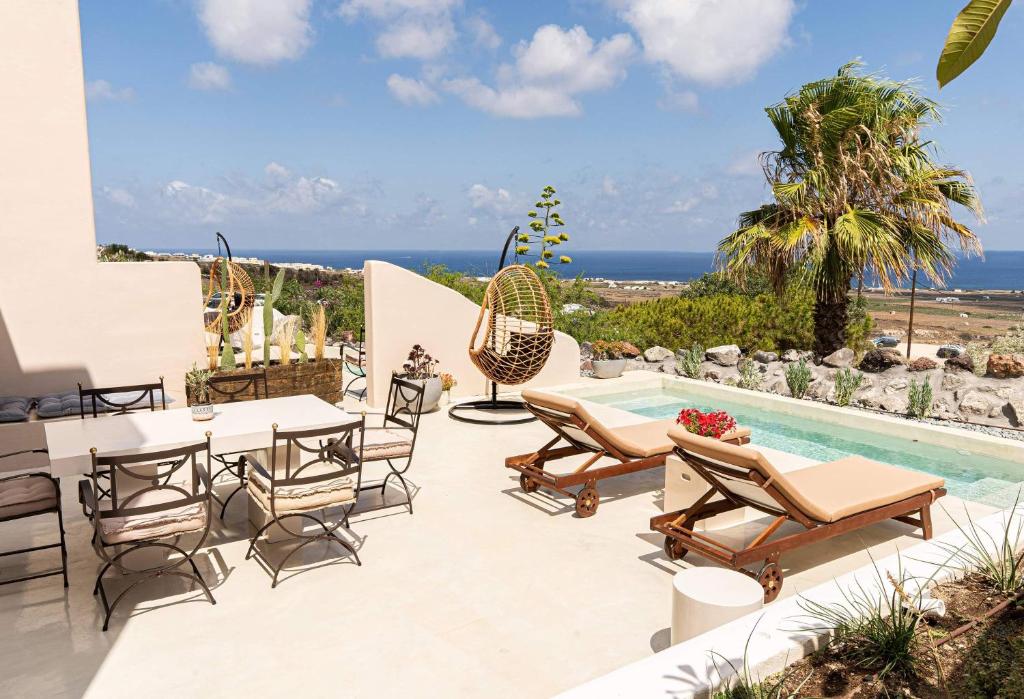 a patio with a table and chairs next to a pool at Pink Freud Villas Santorini in Oia