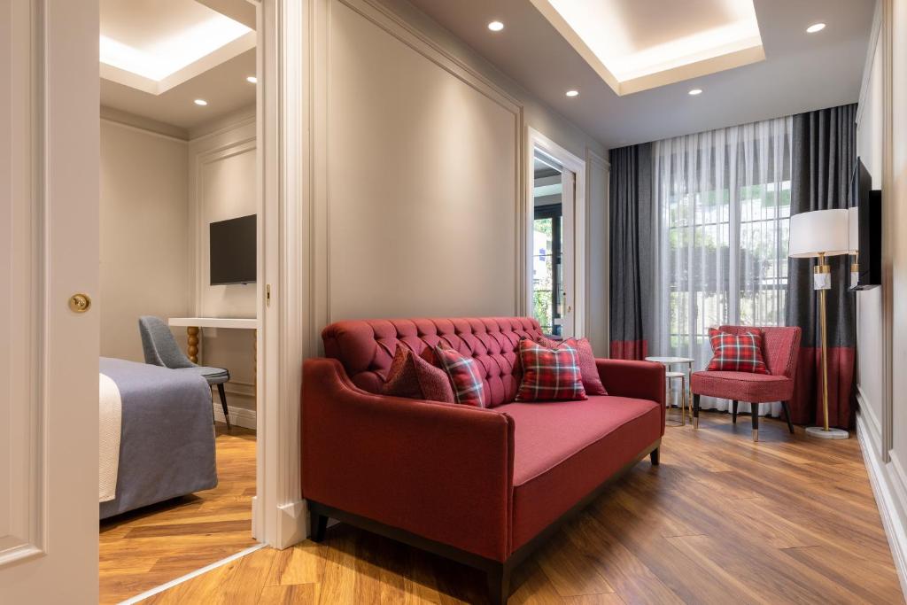 a living room with a red couch and a bedroom at Motif Hotel Çeşme in Çeşme