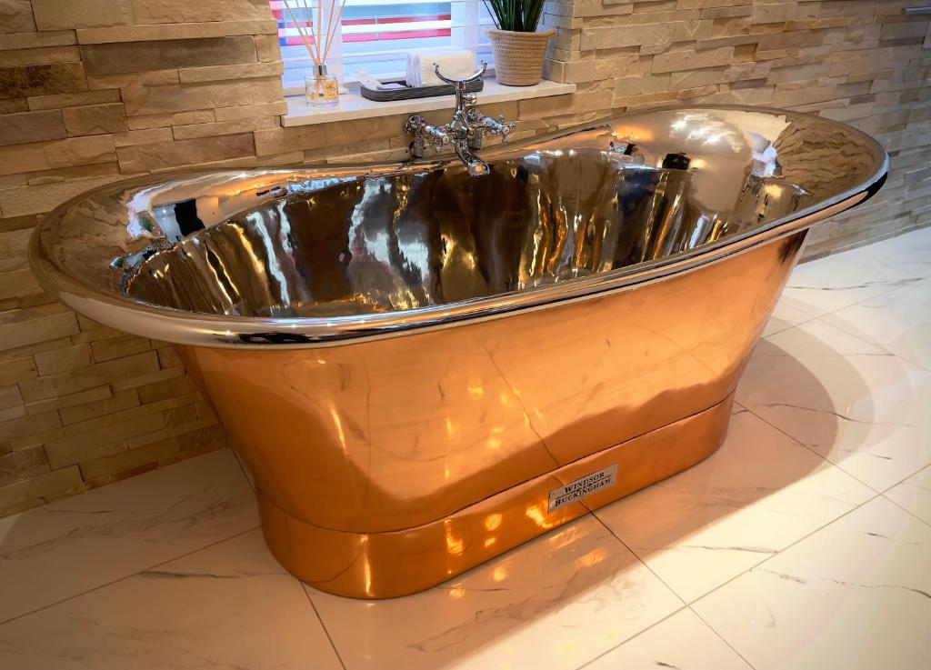 a copper tub in a bathroom with a sink at Pamper yourself in our DOUBLE SIZED copper tub -2 bedroom villa in Inverness
